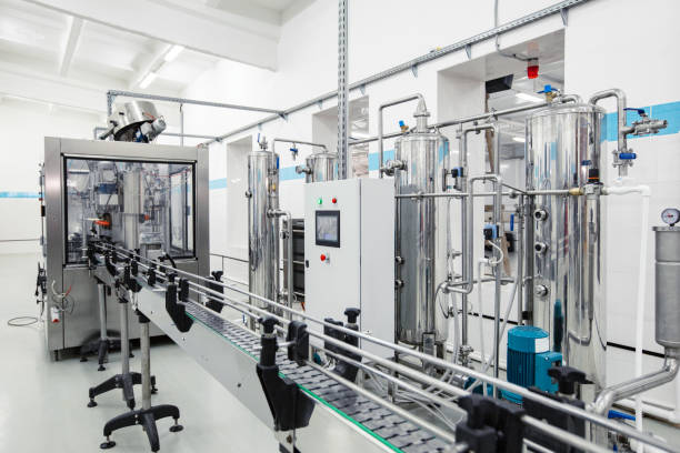 A highly efficient processing line displays stainless steel equipment in a bright, organized factory setting. Machinery operates along a conveyor, ensuring smooth production capabilities.
