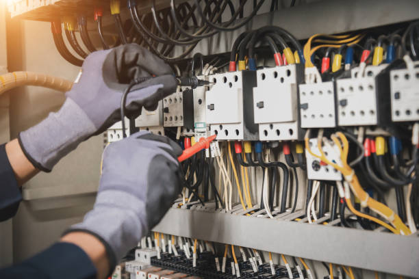 Electricity and electrical maintenance service, Engineer hand holding AC multimeter checking electric current voltage at circuit breaker terminal and cable wiring main power distribution board.
